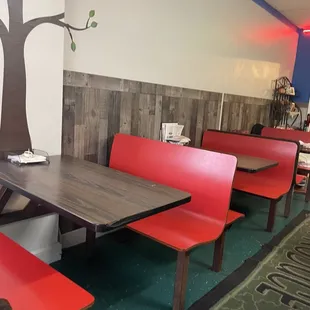 red booths with a tree painted on the wall