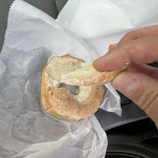 a person holding a bagel in their hand