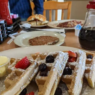 Belgian waffles up front, turkey sausage, corn beef hash, bagel sandwich in background