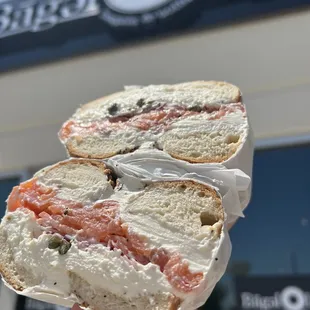 a hand holding a bagel with a bite taken out of it