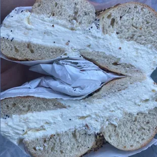 a person holding a bagel with cream cheese