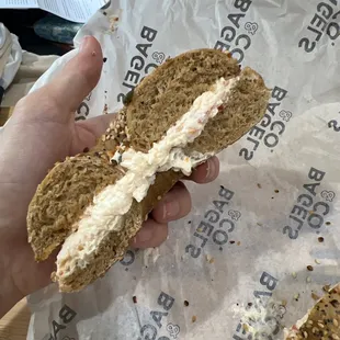 a hand holding a half eaten bagel