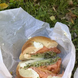 Salmon, capers, red onion, tomato, cucumber, sprouts, and cream cheese on a plain bagel