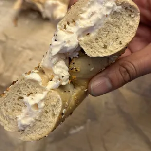  hand holding a bagel with a bite taken out of it