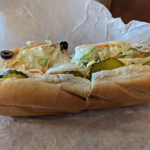 Tuna salad sandwich with pickles, carrots, hard boiled eggs, lettuce, and black olives