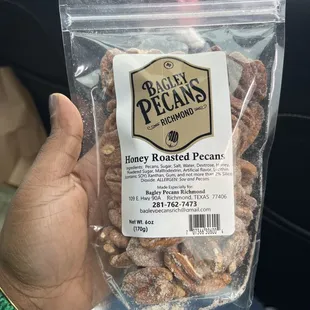 a hand holding a bag of honey roasted pecans
