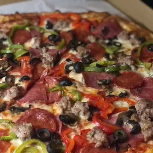 a pizza with pepperoni, olives, and sausage