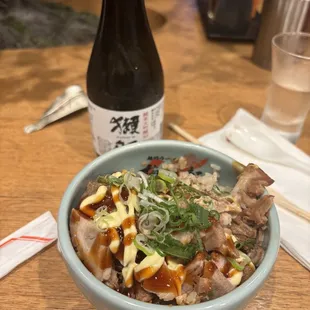 Small bowl with rice, pork, and sauces (can't recall the name) with some sake!