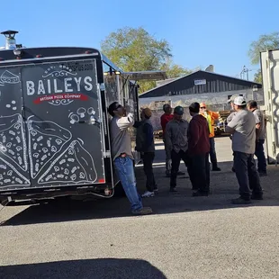 a group of people standing in front of a food truck