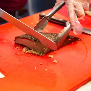 a person cutting meat on a cutting board