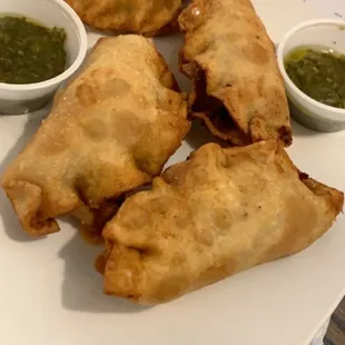 a plate of pastries with dipping sauces
