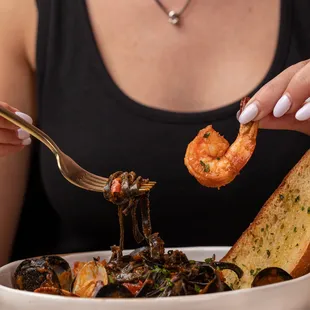 a woman eating a bowl of seafood