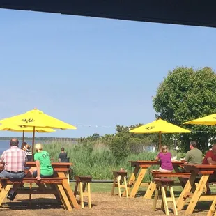 people sitting at picnic tables with yellow umbrellas