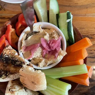 a plate of hummus, carrots, cucumbers, and bread