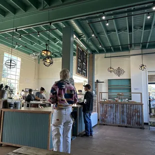 a woman standing at the counter of a coffee shop