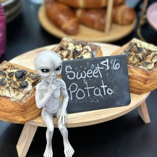 a small alien sitting on a plate of pastries