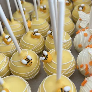 a tray of cake pops with bees on them
