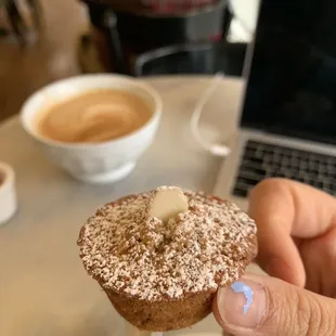 a person holding a doughnut in front of a laptop