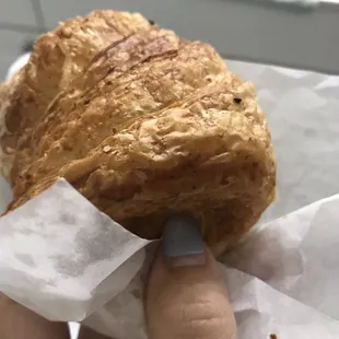 a hand holding a croissant