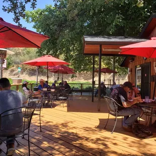 people sitting at tables with red umbrellas