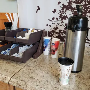 a coffee maker, coffee cups, and other condiments