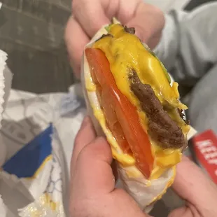 a hand holding a cheeseburger