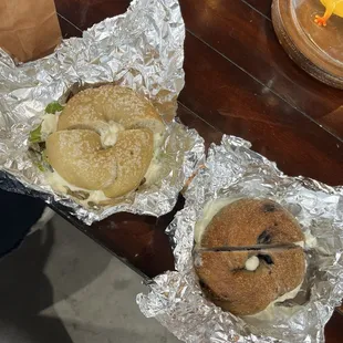 Salt bagel with avacado and cream cheese and a blueberry bagel with cream cheese
