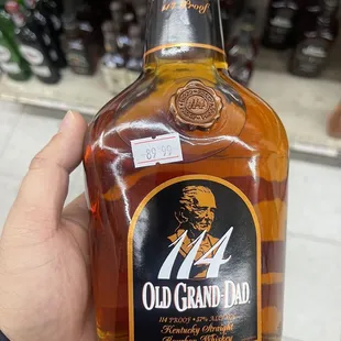 a hand holding a bottle of old grand dad