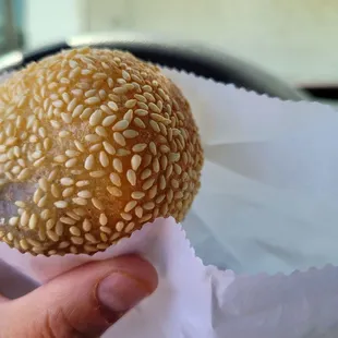 a hand holding a sesame bun