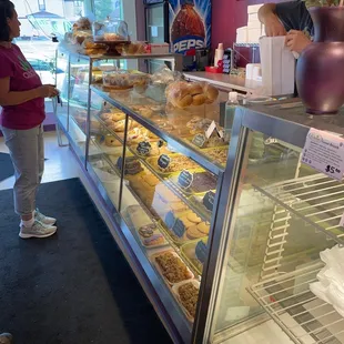 a woman standing in front of a display of pastries