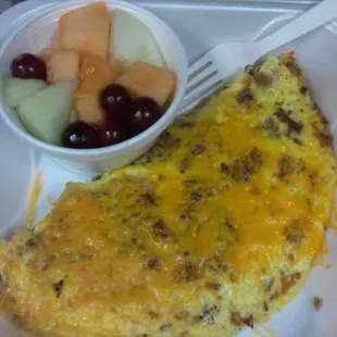 Cup of fruit with a sausage and bacon omelet.