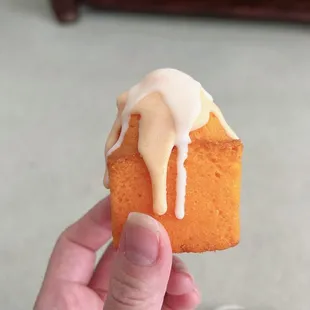 a hand holding a piece of cake with icing