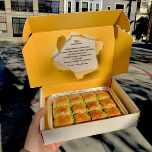 a person holding a box of baklats