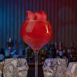 a red drink with rose petals on the table