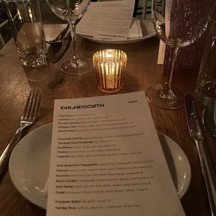 a table setting with a menu and wine glasses