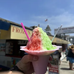 a hand holding a pink paper plate with a colorful ice cream cone