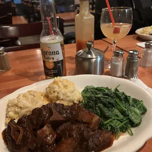 a plate of beef with mashed potatoes and spinach