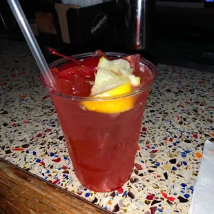 a red drink with a lemon wedge