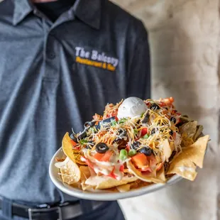 a man holding a plate of nachos