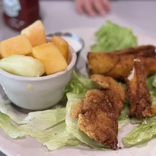 a plate of fried chicken, lettuce, and melon
