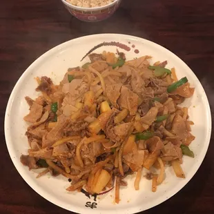 a plate of stir fried noodles and a bowl of rice