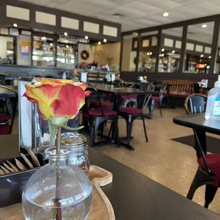 a flower in a vase on a table in a restaurant