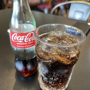 a glass of coke and a bottle of coke