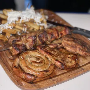 a wooden cutting board with meat and potatoes