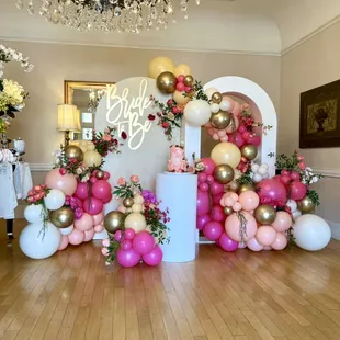 How beautiful is this very custom photo display with arched walls, florals in the balloon garland and wall sign. All provided by Balloon it!