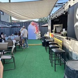 people sitting at tables under a shade