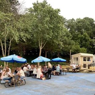 a group of people sitting at tables under blue umbrellas