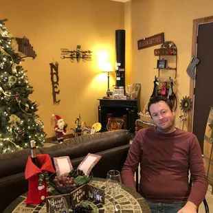 a man sitting at a table in front of a christmas tree