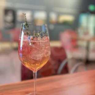 a glass of wine with a sprig of thyme