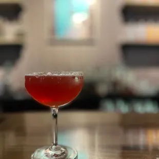 a red cocktail in a coupe glass